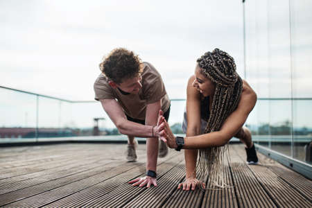 Young couple doing exercise outdoors on terrace, sport and healthy lifestyle concept.