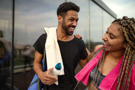Young couple talking after exercise outdoors on terrace, sport and healthy lifestyle concept.の写真素材
