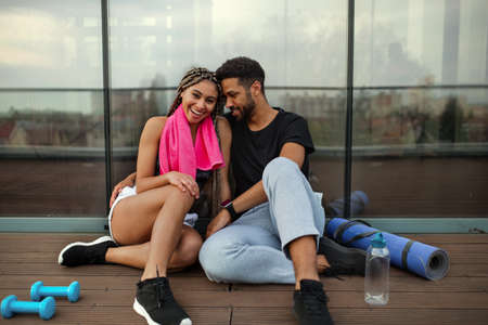 Young couple in love resting after exercise outdoors on terrace, sport and healthy lifestyle concept.の写真素材