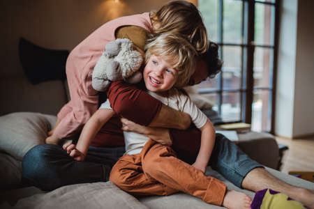 Mature father with two small children resting indoors at home, playing.