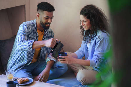 Happy couple sitting, resting and drinking coffee indoors in a tree house, weekend away and digital detox concept.の写真素材