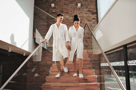 Portrait of young couple in spa resort, walking down the stairs.の写真素材