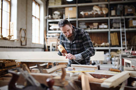 Portrait of mature male carpenter working on his product. Small business concept.