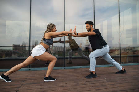 Young couple doing exercise workout outdoors on terrace, sport and healthy lifestyle concept.の写真素材