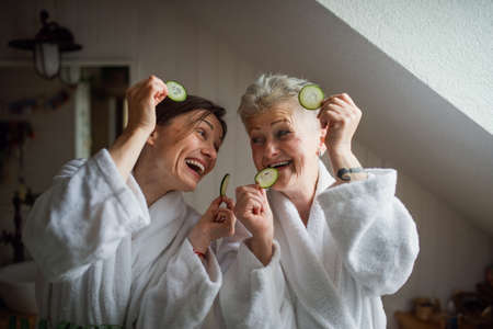 Happy senior mother in bathrobe with adult daughter indoors at home, selfcare concept.の写真素材