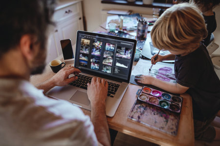 Unrecognizable father with two small children working indoors at home, painting pictures and home office concept.の写真素材