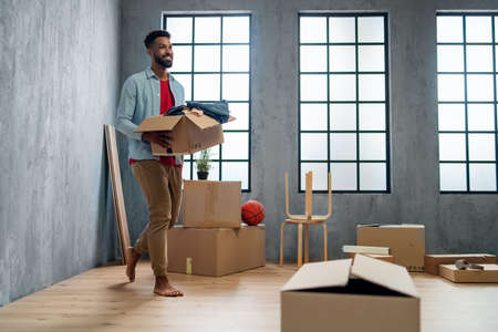 Happy young man holding packing boxes moving home, new living concept.