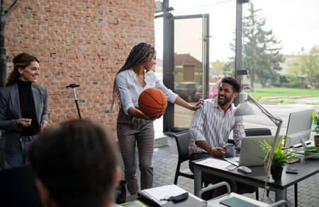 Cheerful young businesswoman having fun with ball in office, take a break concept.の写真素材