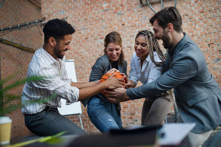 Group of cheerful young businesspeople playing basketball in office, taking a break concept.の写真素材