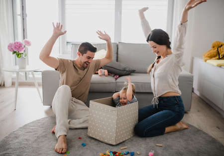 Happy young family with little daughter playing and having fun together at home.