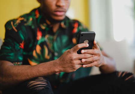 Portrait of unrecognizable young man using smartphone, sitting on sofa at home, social networks concept.の写真素材