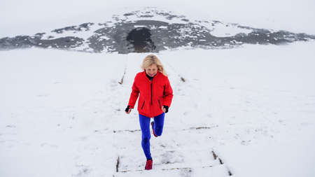 High angle view of active senior woman outdoors in snowy winter, running.