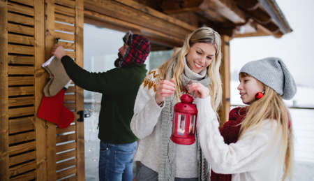 Family with small daughter decorating terrace of house outdoors in winter, Christmas time.の写真素材