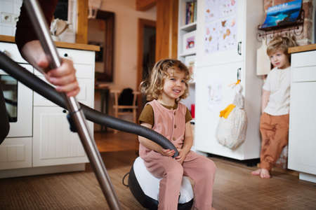 Unrecognizable father with small children hoovering indoors at home, daily chores concept.の写真素材