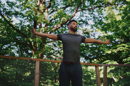 Low angle view of happy young man doing exercise outdoors on terrace of tree house, weekend away and digital detox concept.の写真素材