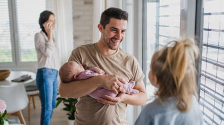 Happy young family with newborn baby and little girl enjoying time together at home.の写真素材