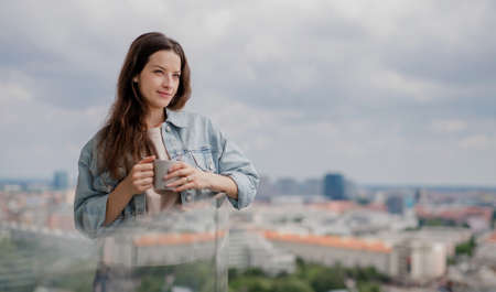 Portrait of young caucasian woman with coffee outdoors on balconyの写真素材