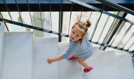High angle view of little girl walking up the stairs indoors.の写真素材