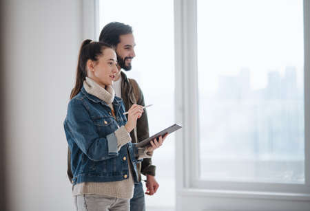 Young couple with tablet moving and planning in new flat, new home and relocation concept.