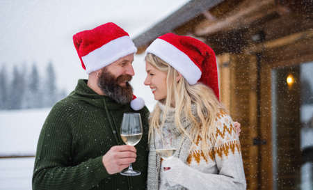Happy couple in love drinking wine on terrace outdoors in winter nature, holiday at Christmas time.の写真素材