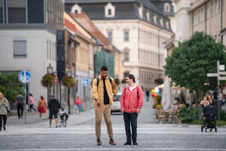 Young man with Down syndrome and his mentoring friend walking and talking outdoors