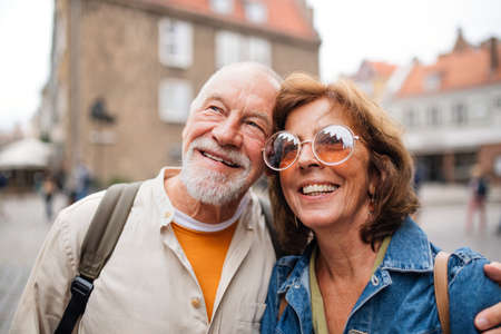 Portrait of happy senior couple tourists hugging on trip in townの写真素材
