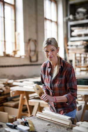 Female carpenter with goggles working on her product, looking at camera. Small business concept.の写真素材