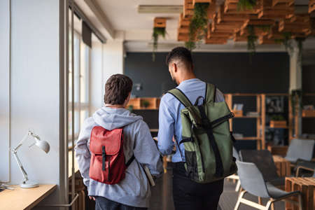 Rear view of young man with Down syndrome and his tutor indoors at schoolの写真素材