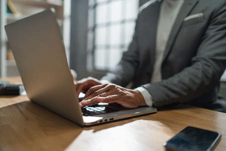 Close up of african american businessman working on a laptop indoors in office