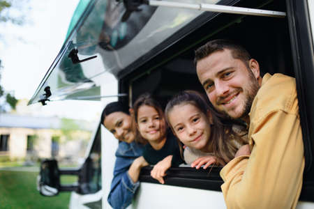 Happy young family with two children looking out of caravan window.の写真素材