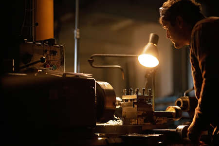 Industrial man working indoors in metal workshop at night.の写真素材