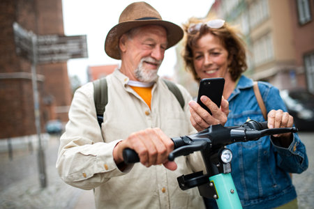 Close up of happy senior couple tourists scanning code to rent a scooter together outdoors in townの写真素材