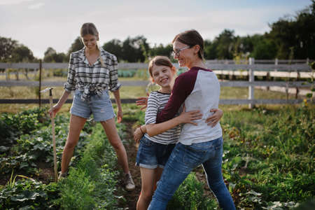 Happy little girl with mother hugging outdoors at community farm.の写真素材