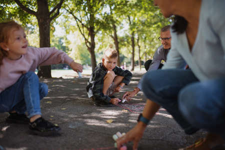 Senior couple with grandchildren drawing with chalks on pavement outdoors in park.の写真素材