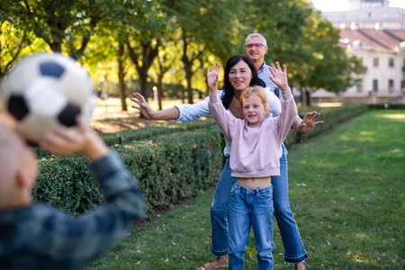 Happy little children with grandparents playing with football outdoors in parkの写真素材
