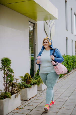 Happy overweight woman in sports clothes outdoors on the way to fitness centerの写真素材