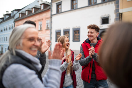 Diverse group of happy community service volunteers claping hands outdoors in streetの写真素材