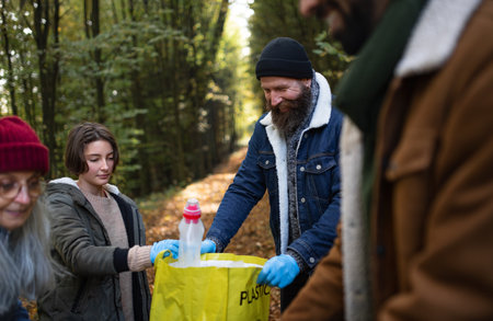 Diverse group of volunteers cleaning up forest from waste, community service conceptの写真素材
