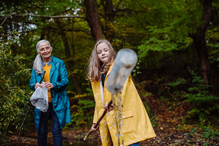 Small girl with grandmother showing plastic waste what they found outoors in forest.の写真素材