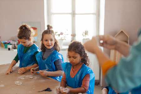 Group of little kids working with pottery clay during creative art and craft class at school.の写真素材