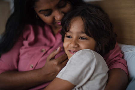 Close-up of indian mother hugging her little son at home.の写真素材