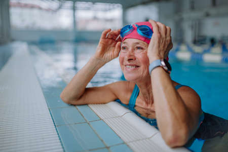 Happy senior woman in swimming pool, leaning on edge.の写真素材