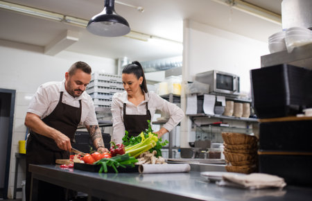 Chef teaching how to cook, cutting vegetables indoors in commercial kitchen.
