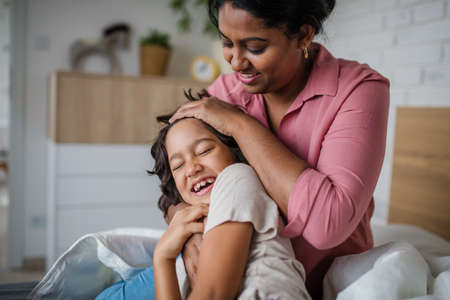 Indian mother hugging her little son and having fun at home.
