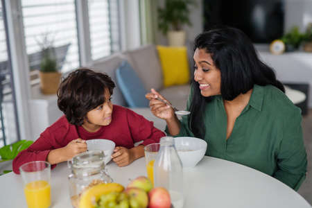 Little boy having breakfast with his mother at home.