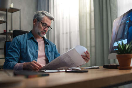 Mature man architect working on computer at desk indoors in office.の写真素材