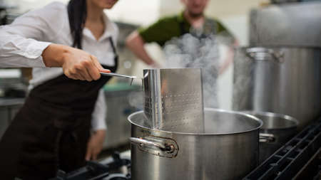 Unrecognizable chef and cook cooking together indoors in restaurant kitchen.の写真素材