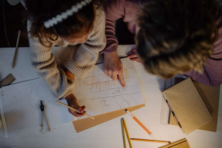 Top view of little girl doing homework with her mother in evening at home.の写真素材