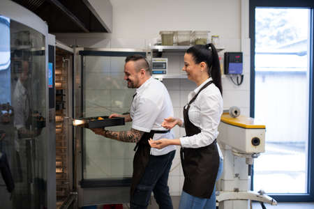Happy chef and cook working on their dishes indoors in restaurant kitchen.