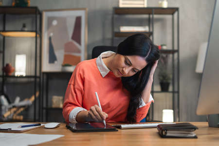 Happy mid adult woman working indoors in office.の写真素材